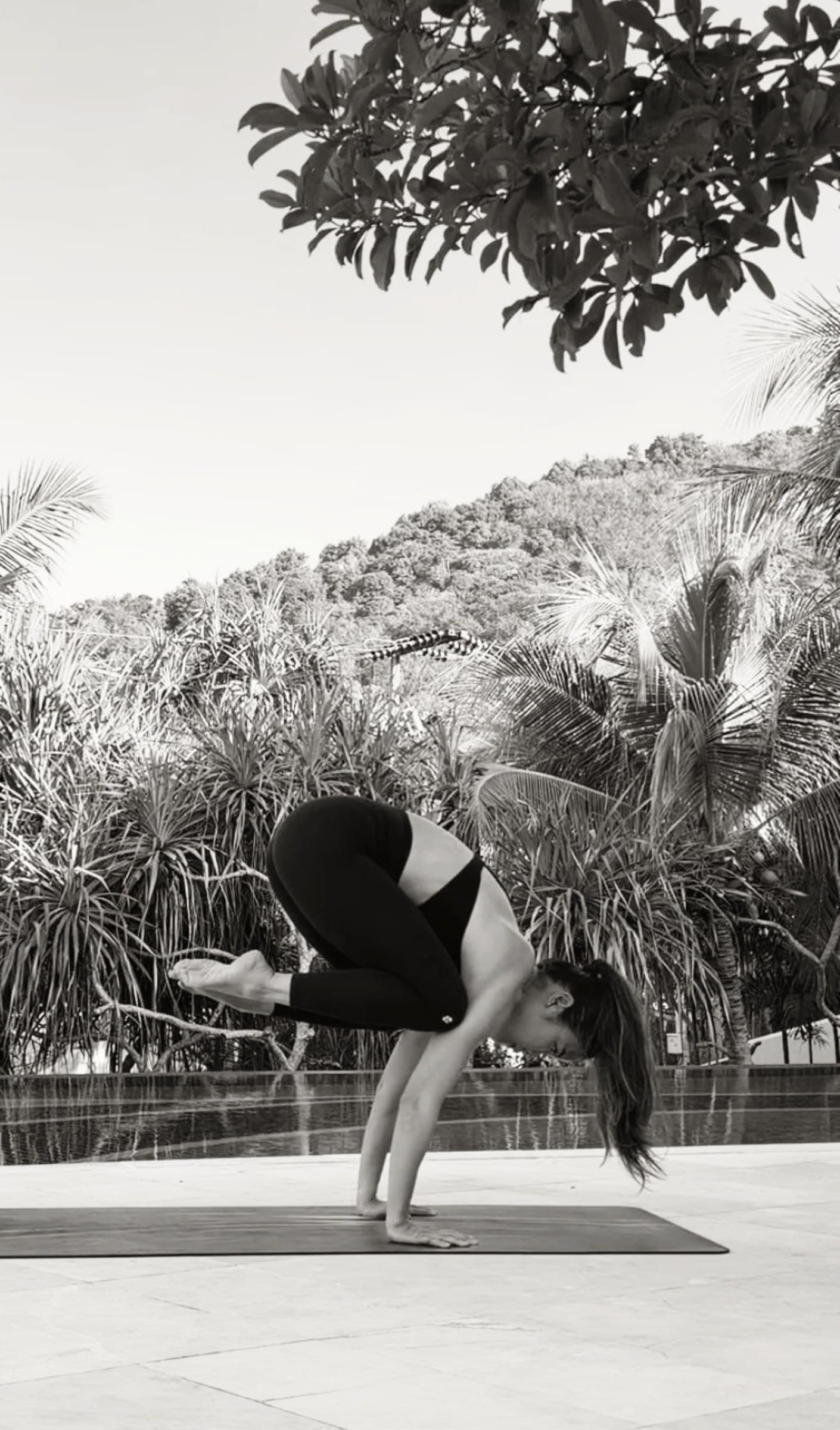 Soulena in crow pose on a deck by the pool